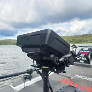 Perched on the boat like a sentinel of the seas, the sleek black Humminbird Visor from BerleyPro sits ready for action. Against a backdrop of serene, cloudy skies and distant tranquil trees, this piece of tech blends elegance with unyielding functionality. Whether you're charting new watery frontiers or standing vigilant over familiar fishing grounds, this visor's got your back—and the view's never looked better.
