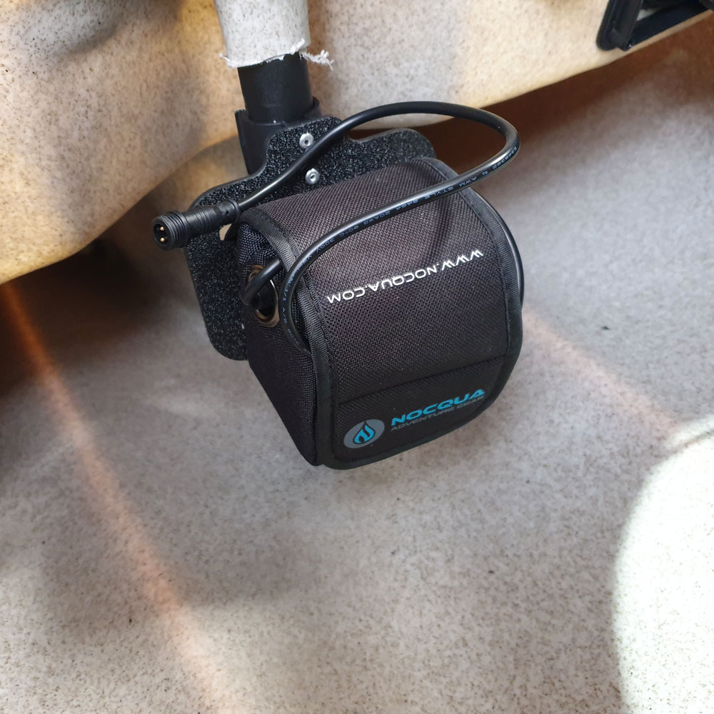 Nestled under a sleek beige surface, you've got your compact black battery pack all sorted. It's snugly secured in a Nocqua 25mm (1 Inch) Shaft Battery Mount, keeping everything tidy and efficient. Ready to power up without a fuss!.