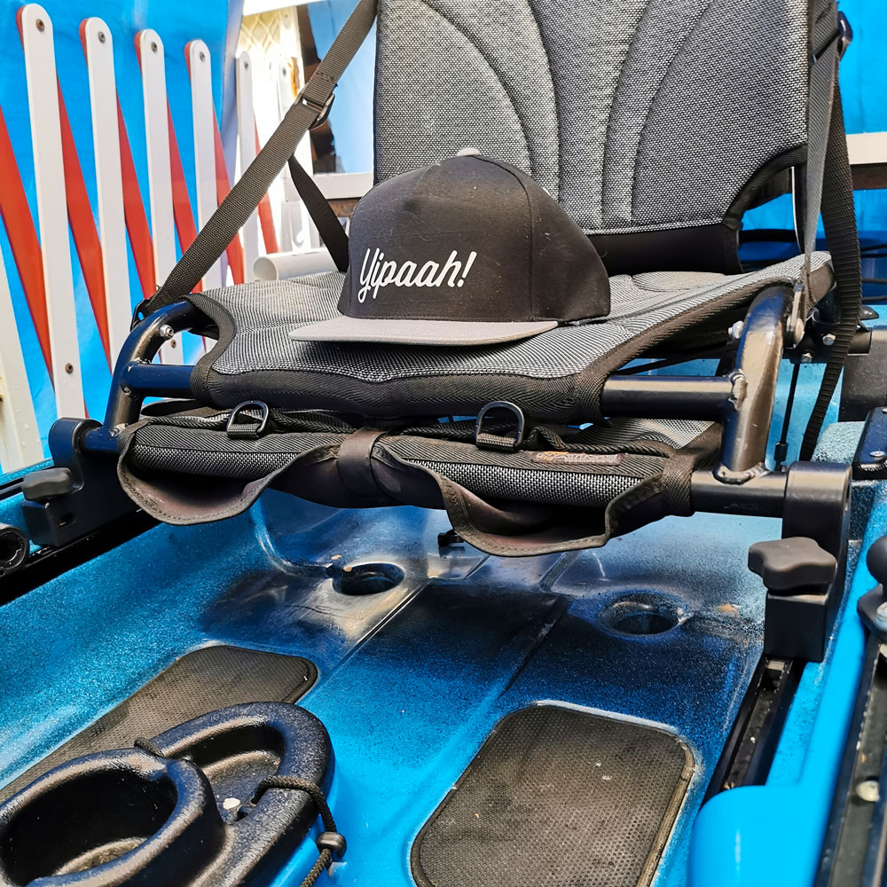 Inside the sleek blue kayak, perched on a grey padded seat enhanced by Native Watercraft Slayer Seat Risers, sits a stylish baseball cap adorned with the spirited "Yipaah!" text. Get ready to make waves in style!.