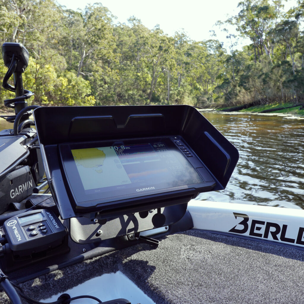 Cruising down the river, this fishing boat is decked out with a Garmin Visors unit that’s got your back for sonar and navigation. It's cutting through the water with ease, surrounded by a canopy of lush trees and vibrant greenery.