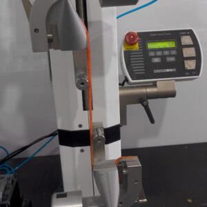 Check it out! We've got this tensile testing machine doing its thing, cradling an orange sample that could easily pass for one of our Jerkshads. It's nestled comfortably between the grips, and right there in action is a digital control panel that's as precise and reliable as the Catch Black Label Livies Jerkshad itself. Speed settings? Yeah, it nails those too. Talk about engineering that knows exactly what it's doing!.