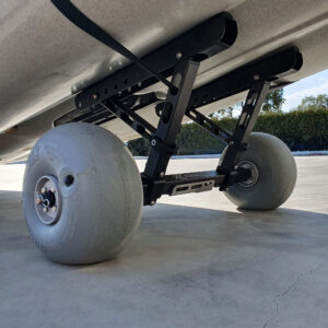 Catch a close-up glimpse of the Kimmi Cart - your ultimate kayak trolley companion! Sporting rugged gray, textured tires and a sleek black metal frame, this powerhouse is ready to roll over any terrain. Set against a backdrop of greenery with its sturdy design standing firm on concrete, the Kimmi Cart is as reliable as it gets for your kayaking adventures.
