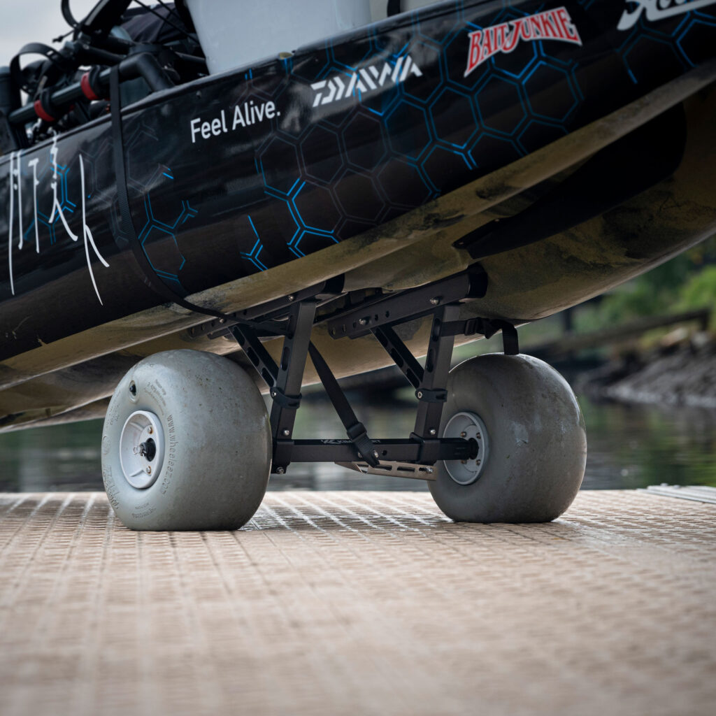 Check out this awesome shot of a boat rocking some big wheels down at the dock, flaunting those hexagonal patterns and stickers on its side. It's got that slick look reminiscent of the Kimmi Cart - Kayak Trolley, designed to slide you into adventure effortlessly.