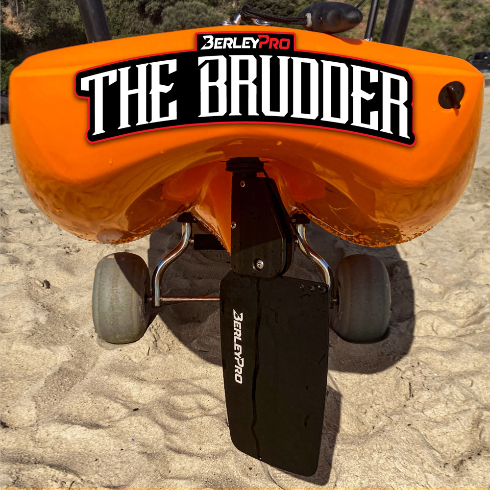 Introducing the Brudder by BerleyPro – where performance meets innovation on a sandy shoreline. This vibrant orange kayak, featuring a robust black rudder for ultimate maneuverability, is complemented by handy small wheels to make transportation a breeze. Experience kayaking like never before with the Brudder's seamless blend of style and practicality!.