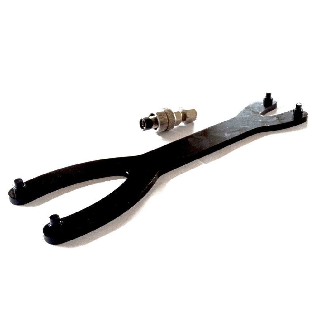 Introducing the sleek black spanner wrench, featuring dual prongs on both ends, set against a crisp white background alongside a trusty metal threaded coupling adapter. This dynamic duo is an essential component of the Native Watercraft Propel Service Spanner Kit. Elevate your maintenance game and enhance propulsion efficiency for your Native Watercraft with this powerhouse pair!.