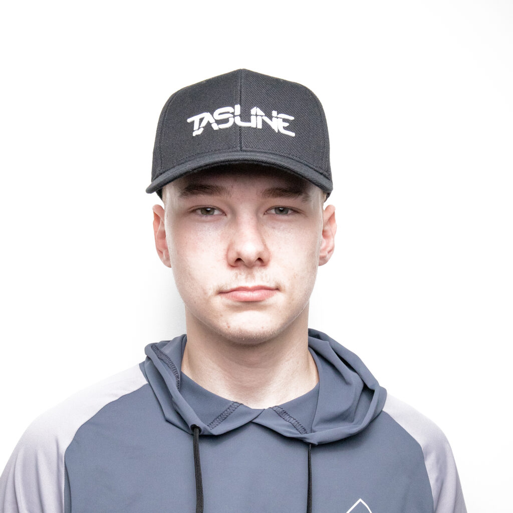 With the stealth of a seasoned angler, this individual dons our Black Tasline Cap with its perfectly crafted Curved Bill, offering shade and style in equal measure. Complementing the cap is a cozy gray and dark blue hoodie that wraps them in comfort like calm waters embrace a kayak. Standing against a stark white backdrop, they’re ready to conquer whatever the day holds—whether it’s casting lines or casually making waves.