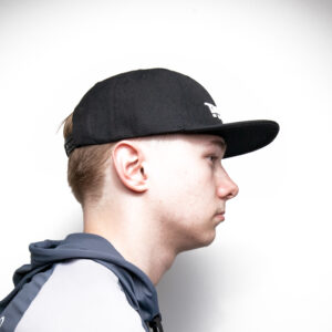 Check out this side shot of a young adventurer rocking the sleek Tasline Cap Flat Bill, paired perfectly with a stylish gray and black jacket. All set against that simple white backdrop, it's an effortless statement of cool and casual style!.